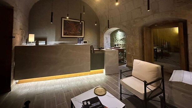 A reception area with a counter, a painting, and a seating area with a chair and a table. - Hotel Piru Wasi Arequipa (Arequipa)