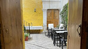 An open doorway leading to a courtyard with stone flooring, outdoor seating, and a yellow wall. - Hotel Piru Wasi Arequipa (Arequipa)