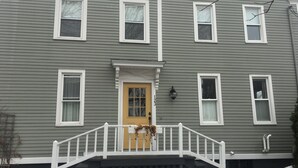 A two-story house with a front porch, a yellow door, and a mailbox. - High End Apartment in Downtown  Hallowell (Hallowell)