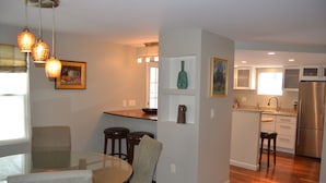 A modern kitchen with a central island, bar stools, and a glass dining table. - High End Apartment in Downtown  Hallowell (Hallowell)