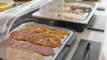 Ein reichhaltiges Buffet mit einer Auswahl an Speisen, darunter Aufschnitt und Käse.