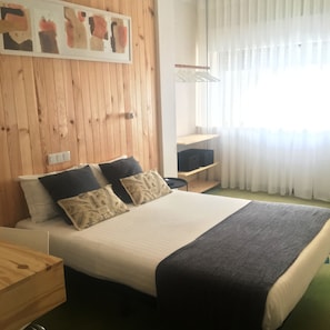 A neatly arranged bedroom with a wooden headboard, a bed with two pillows, a bedside table, and a window with sheer curtains. - Hotel Umu (Santarém)