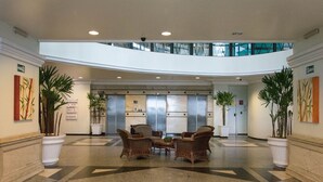 Um hall amplo com área de estar central, elevadores e plantas em vasos.