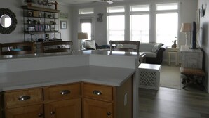 A spacious kitchen with a large island, wooden cabinets, and a ceiling fan. There is a dining area with a sofa and a small table.