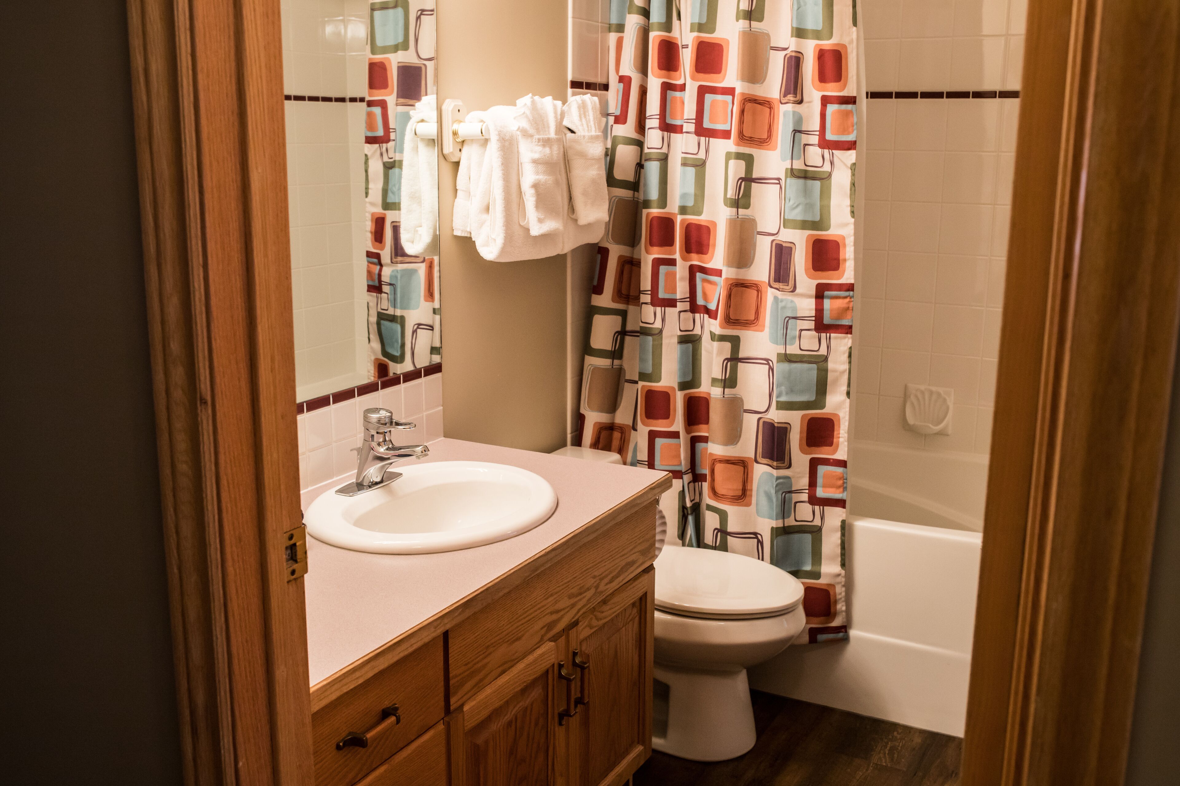 Een badkamer met een wastafel, toilet en bad. Handdoeken hangen aan de muur.