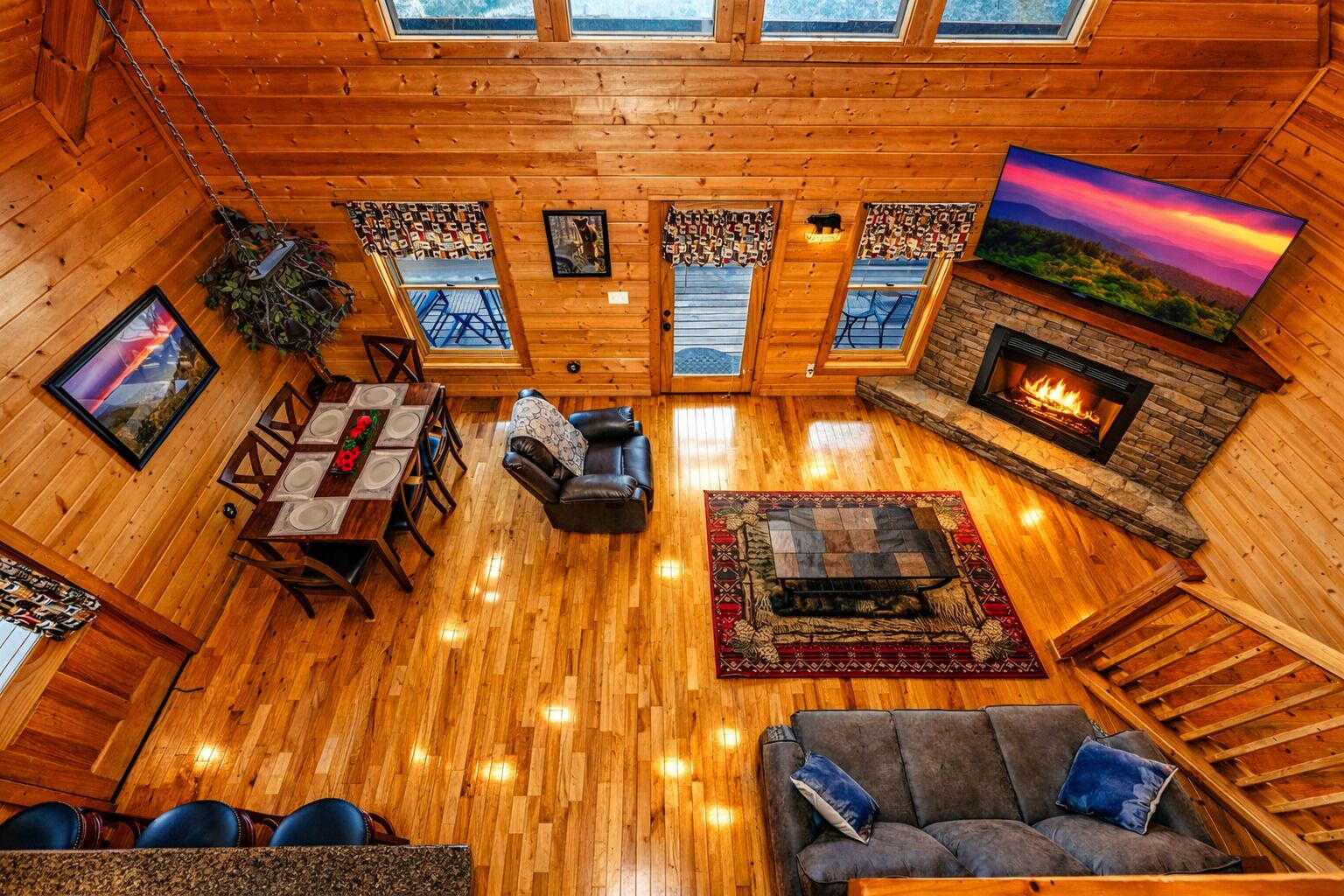 L’intérieur chaleureux d’un chalet comprend un coin repas, une cheminée et une grande fenêtre donnant sur un paysage magnifique.