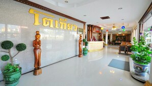 A hotel lobby with a reception desk, seating area, and decorative elements like statues and potted plants. - Tokyo Hotel (Lop Buri)