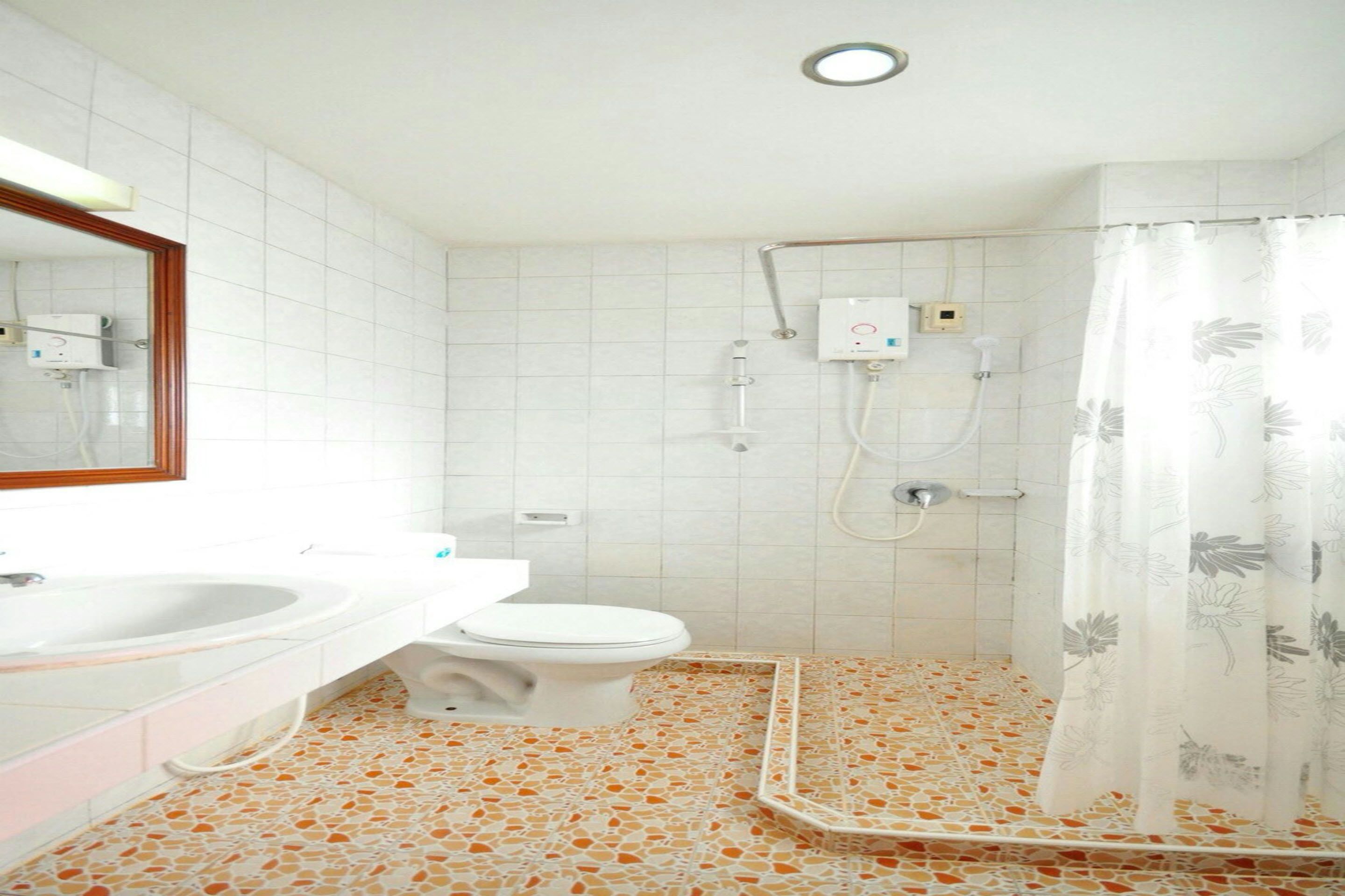 Une salle de bain avec un lavabo, des toilettes et une douche, le tout de couleur blanche.