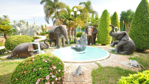 A garden with a central fountain, surrounded by statues of elephants and a frog. - Tokyo Hotel (Lop Buri)