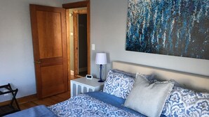 Ein Schlafzimmer mit Bett, Nachttisch, Lampe und einem Bild an der Wand.