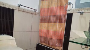 A bathroom with a toilet, a glass sink, and a shower curtain. - Peru Hosting Piura (Piura)
