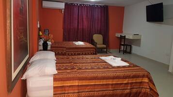 A hotel room with two beds, a desk, a chair, and a TV.