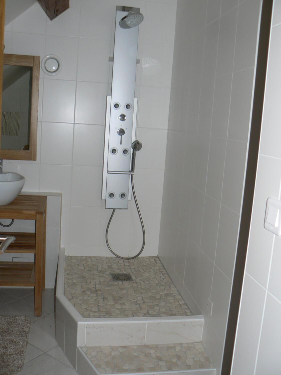 Una dutxa amb panell de control, un rentamans i un mirall.