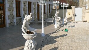A courtyard with stone buildings, white lanterns, and statues. - Le Manoir Des Chapelles (Venoy)