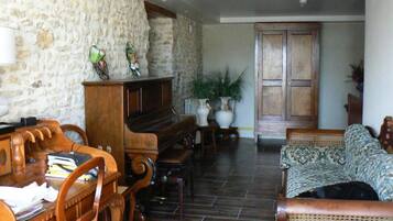 A living room with a piano, a wooden coffee table, a sofa, and a stone wall.