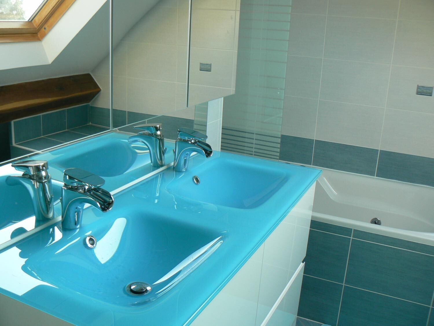 A bathroom with a blue sink, two faucets, and a bathtub.