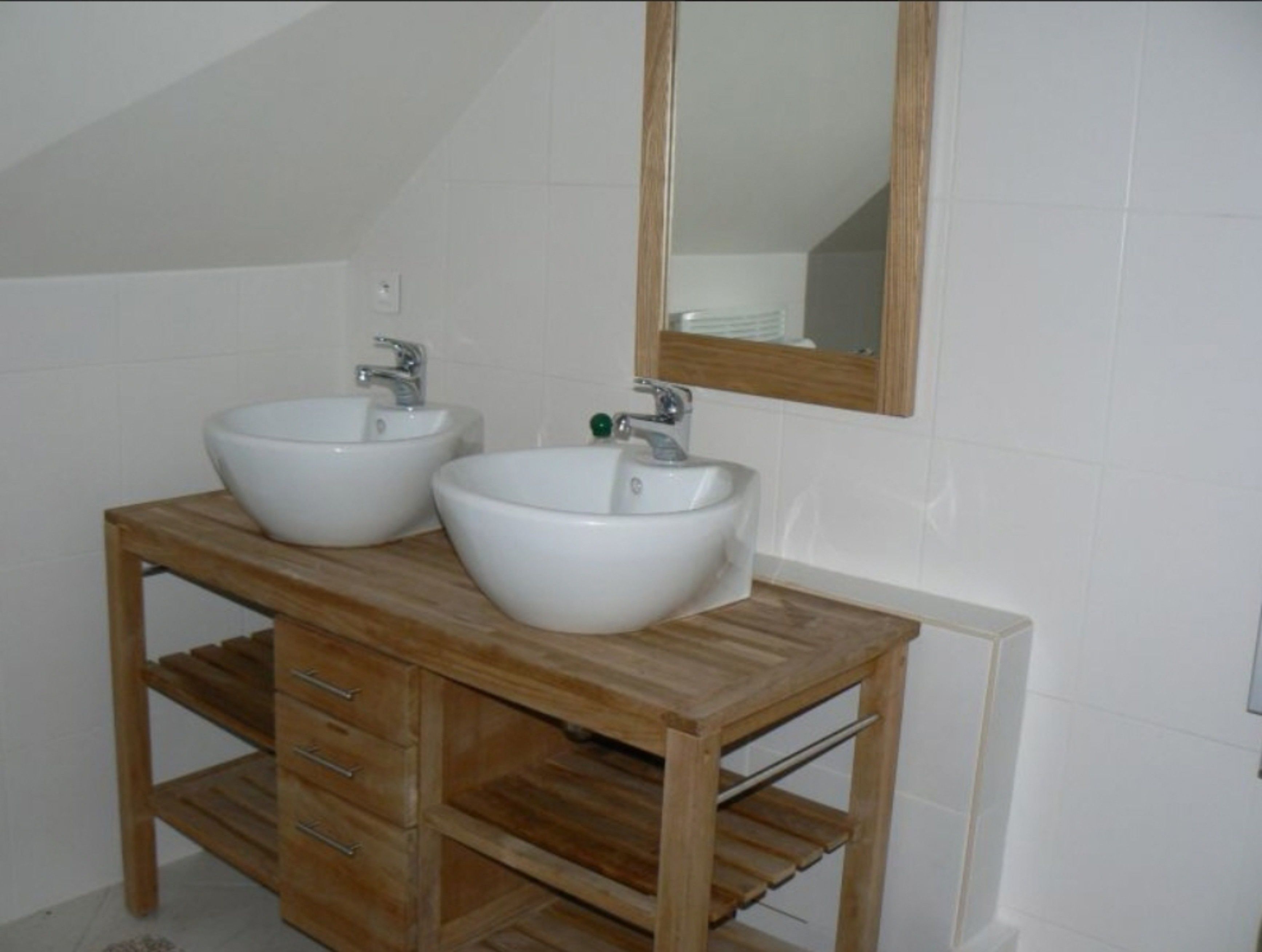 Une salle de bain avec deux lavabos blancs, un meuble-lavabo en bois et un miroir.