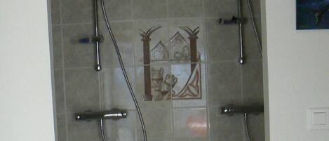 A shower area with a tiled wall, a decorative tile design, and a showerhead.