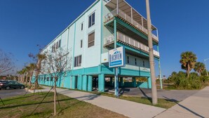 Un immeuble turquoise à plusieurs étages, doté d’un balcon au deuxième étage, sur lequel on peut lire l’inscription « 200 Beachview Condominiums ».