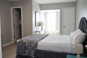 Une chambre à coucher avec un lit, une table de chevet, une lampe et une fenêtre avec des rideaux.