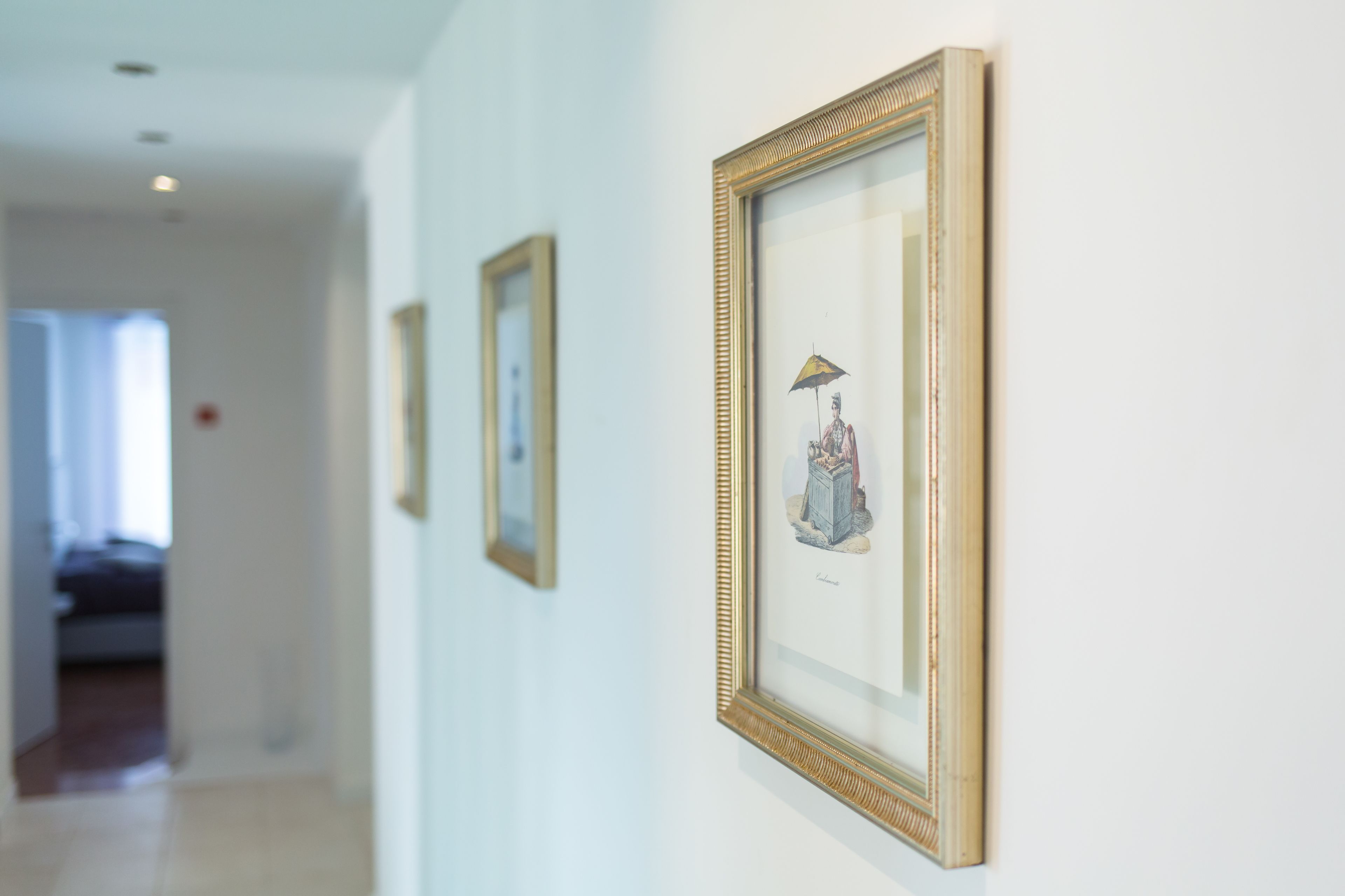 A hallway with framed artwork on the walls.