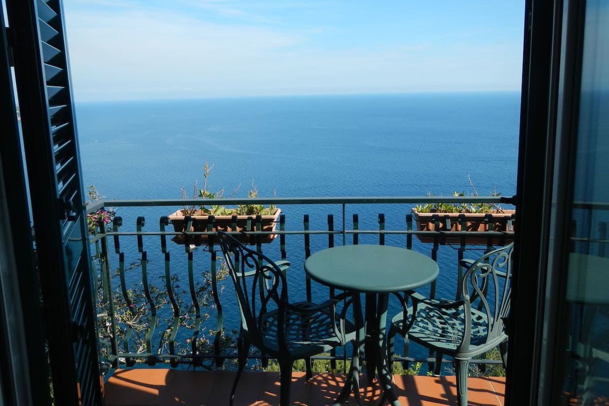 Ein Balkon mit Meerblick, zwei Stühle und ein Tisch.