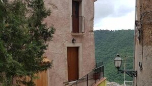 A narrow alleyway with a building featuring a wooden door and a small balcony. - A Taverna Intru u vicu (Belmonte Calabro)