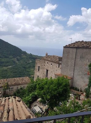A rustic stone building with a tiled roof, surrounded by lush greenery and a mountainous backdrop. - A Taverna Intru u vicu (Belmonte Calabro)