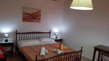 Ein Schlafzimmer mit einem Holzbett, zwei Nachttischen mit Lampen, einem Bild an der Wand und einer Pendelleuchte.