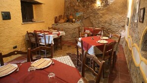 A rustic dining area with stone walls, wooden tables, and chairs. - A Taverna Intru u vicu (Belmonte Calabro)