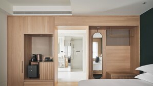 A modern hotel room with a wooden wardrobe, a small desk with a kettle, a bed, and a mirror. - Kimpton Da an Taipei by IHG (Taipei)
