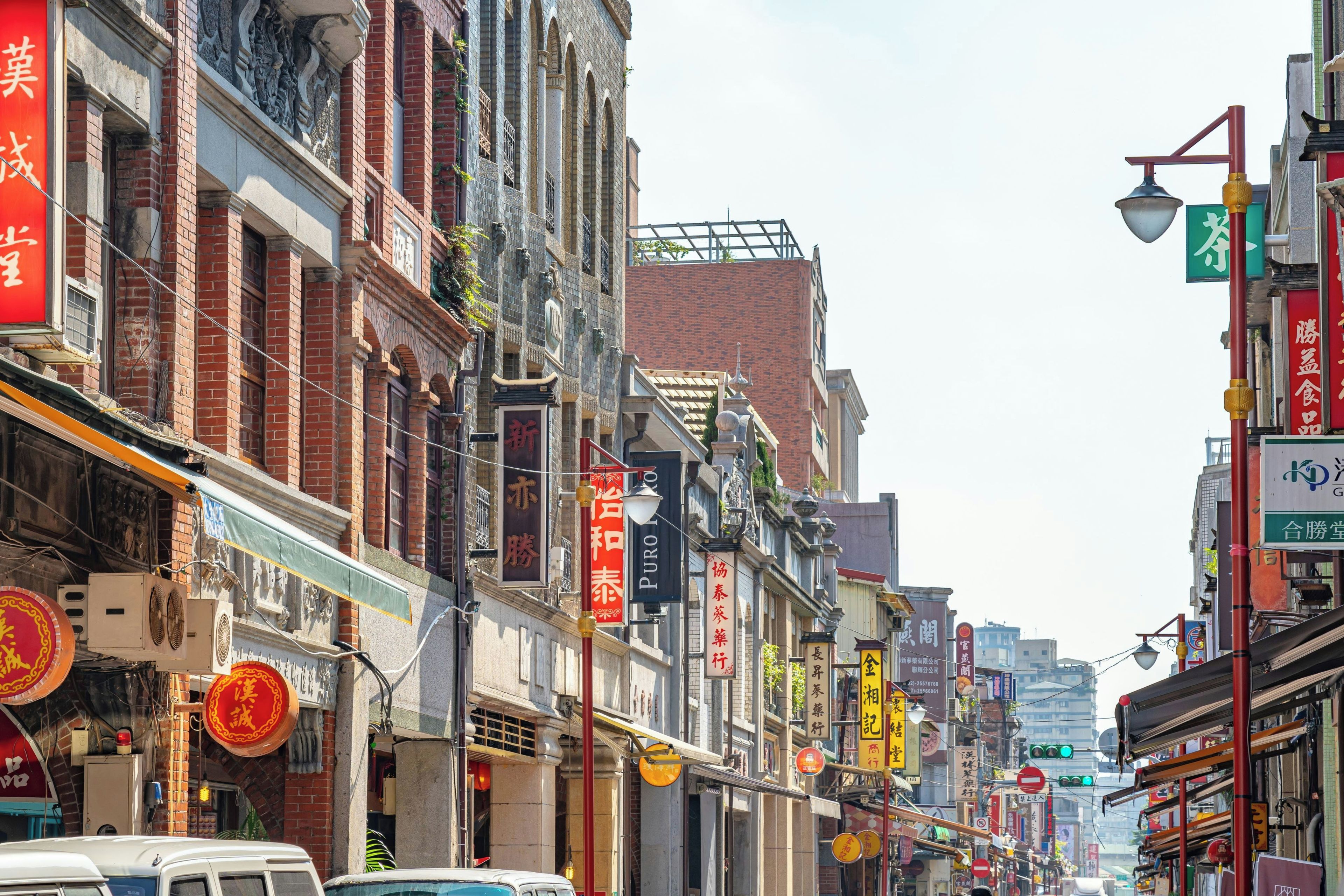 A street lined with traditional buildings, some with signage in a foreign script, and a mix of architectural styles.