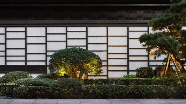 A modern building facade with a grid of windows and a well-maintained garden with a large tree and shrubs. - Kimpton Da an Taipei by IHG (Taipei)