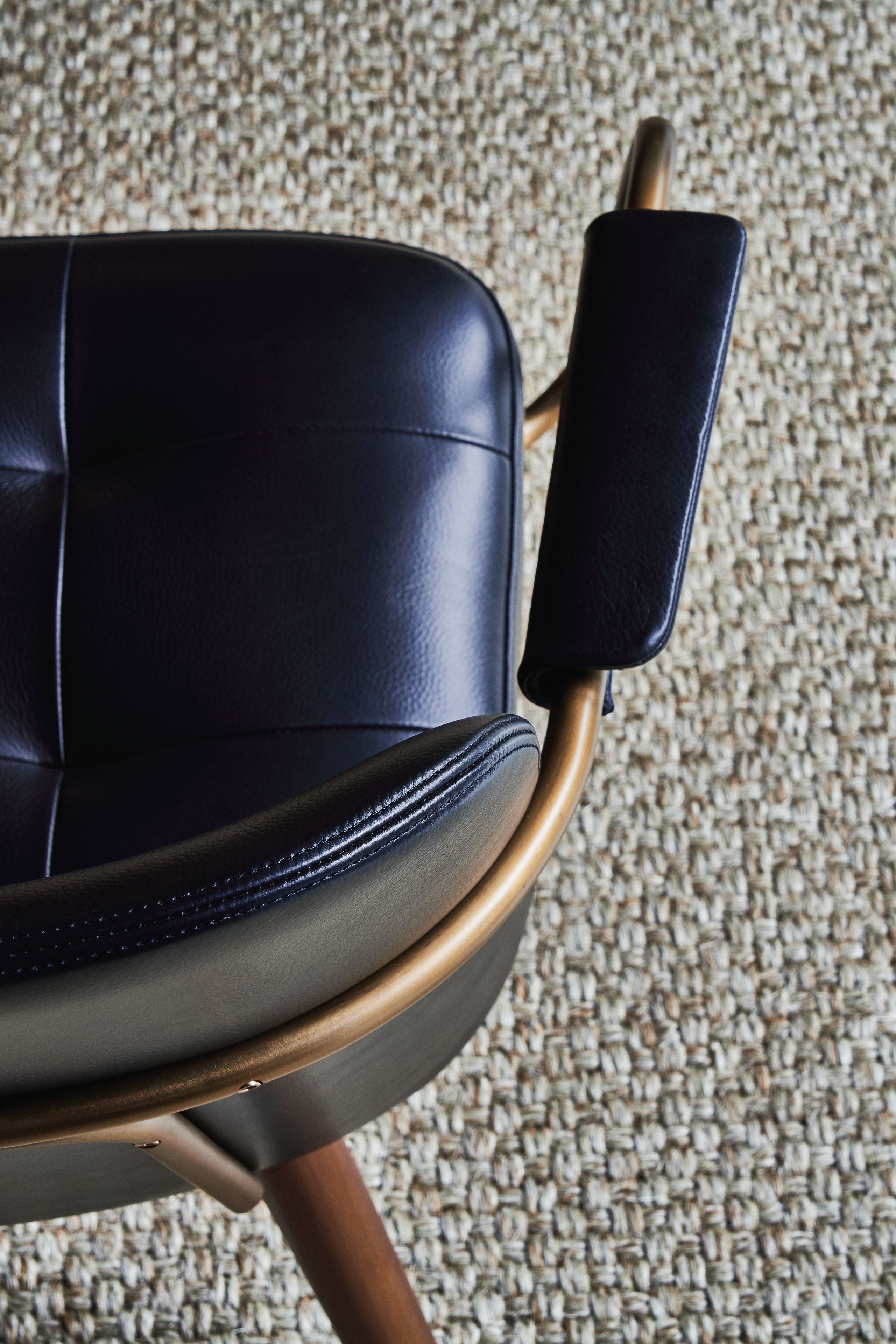 A close-up of a chair with a dark seat and a metallic armrest.