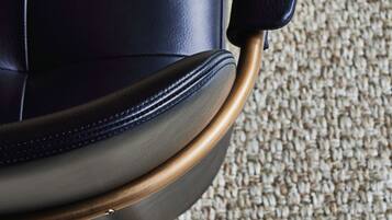 A close-up of a chair with a dark seat and a metallic armrest.