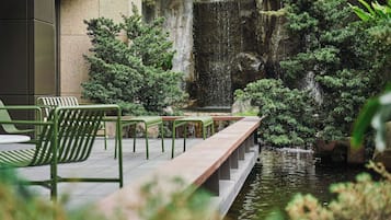 A tranquil outdoor area with a water feature, seating, and greenery.