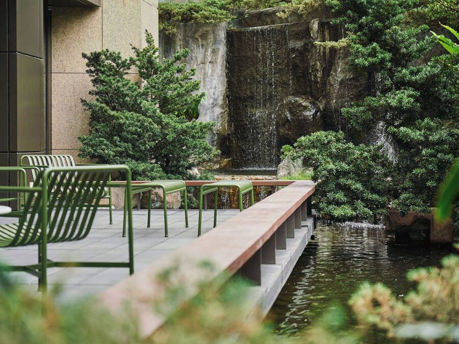 A tranquil outdoor area with a water feature, seating, and greenery.