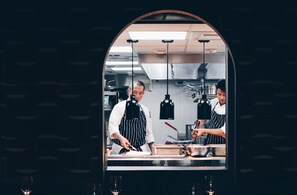 A kitchen with stainless steel appliances, a chef preparing food, and a wine glass on the counter. - Kimpton Da an Taipei by IHG (Taipei)