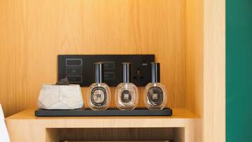 Een houten plank met drie parfumflesjes en een klein decoratief object.
