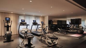 Un gimnasio moderno con cintas de correr, elípticas y pesas libres.