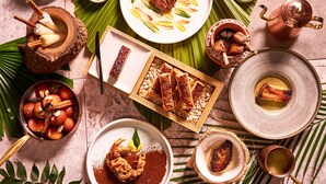 A variety of dishes and food items arranged on a table with a tropical theme, including a roasted meat centerpiece, a bowl of sweets, and several small dishes with sauces. - Kimpton Da an Taipei by IHG (Taipei)