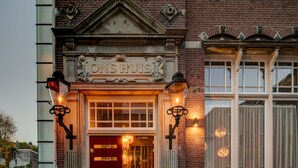 A building facade with a prominent sign reading "ONS HUIS" and a red door, suggesting a commercial establishment. - Hotel Mercier (Amsterdam)