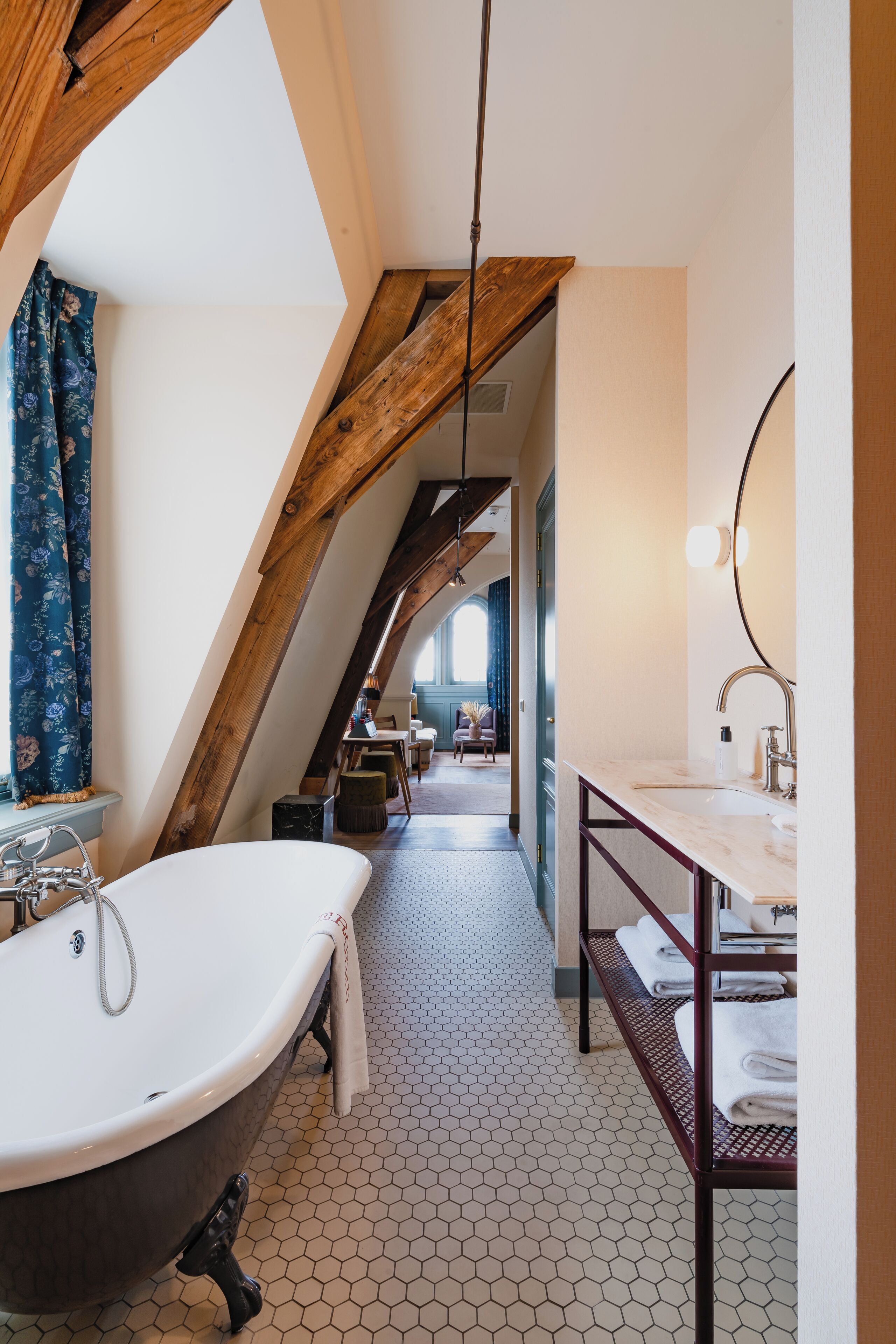 Ein Badezimmer mit freistehender Badewanne, einem Waschtisch mit Spiegel und einem sechseckig gefliesten Boden.