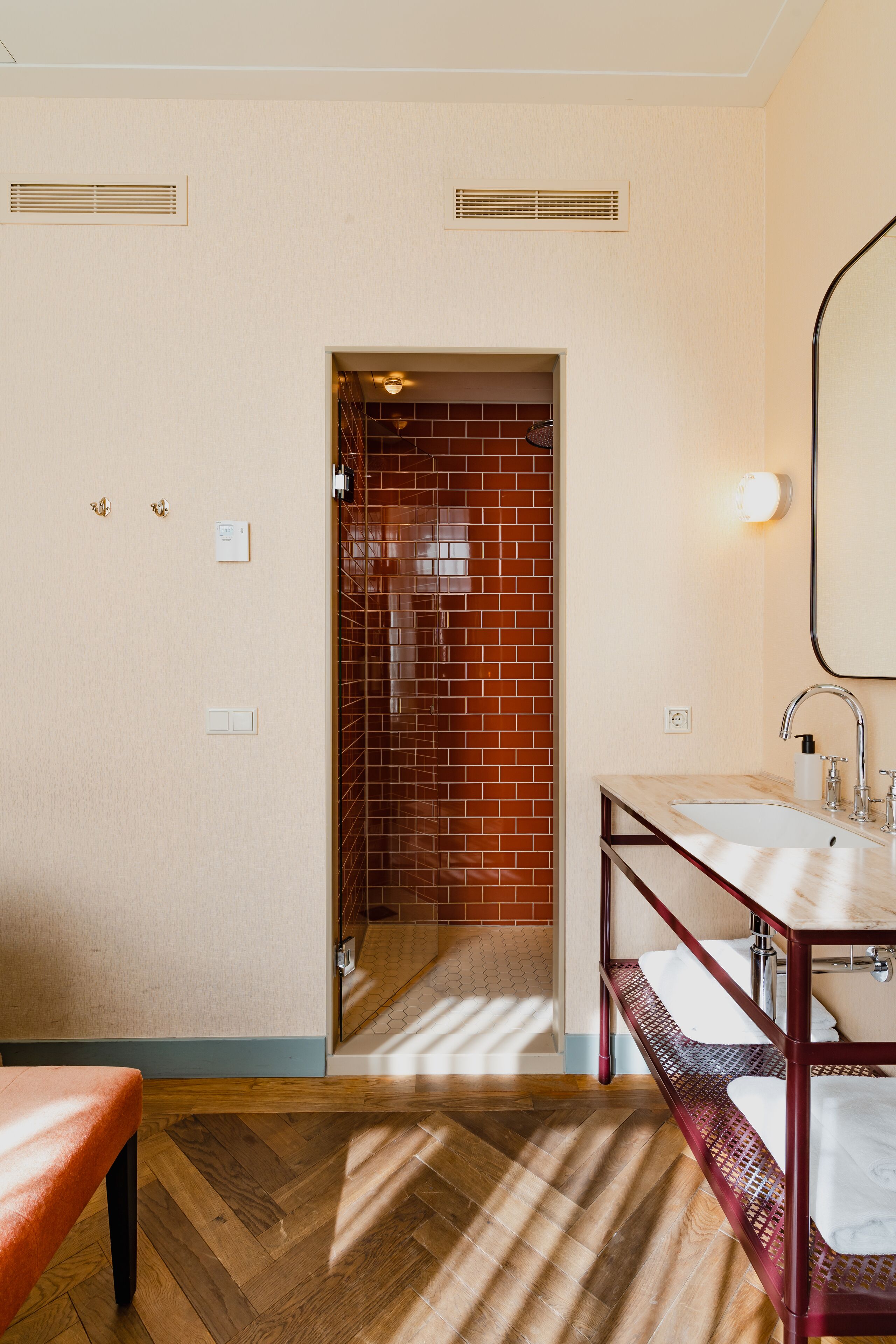 Un baño con suelo de madera, un lavabo con espejo y pared de ladrillo rojo.