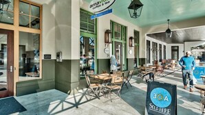 Ein Außenbereich mit Tischen und Stühlen, ein Schild für 'amavida coffee & tea' und ein Schild mit der Aufschrift '30A sold here'.
