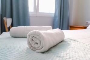A neatly made bed with a white towel rolled at the foot. - Pension Caldas (Caldas de Reis)