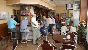 A bar area with stools, a counter, and a television mounted on the wall. - Pension Caldas (Caldas de Reis)