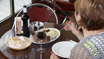 Una mesa de comedor con una botella de vino, una cesta de pan y un plato de comida.
