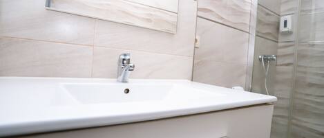 A modern bathroom with a white sink, a mirror, and a glass shower enclosure.