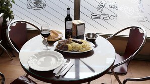 A dining table with plates, cutlery, a bottle of wine, and a basket of bread. - Pension Caldas (Caldas de Reis)